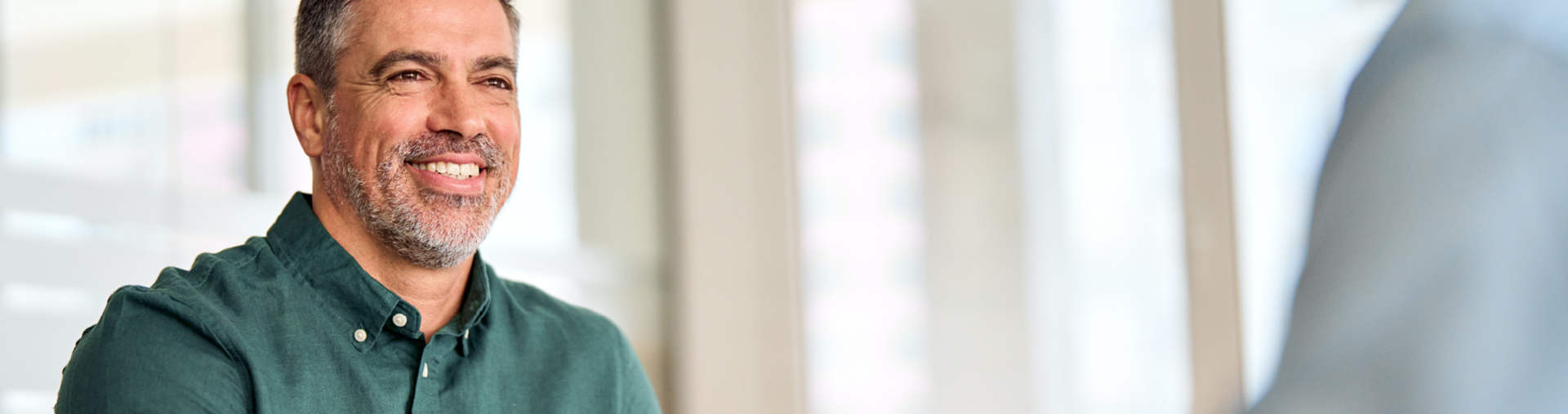 Fachberater im Büro Mann mit Hemd sitzt lächelnd am Schreibtisch