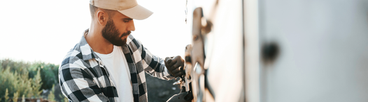 Junger Mann befestigt LKW-Plane an Lkw