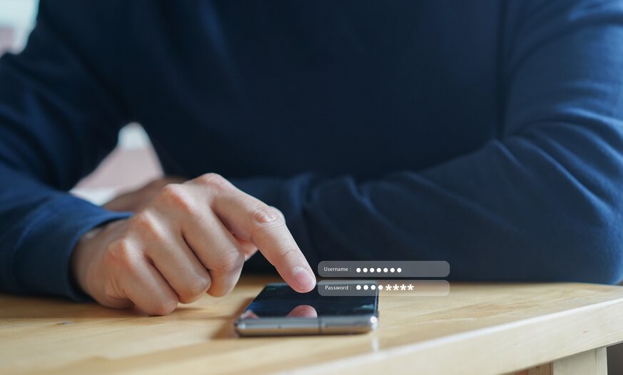 Mann tippt auf Smartphone Benutzernamen und Passwort ein