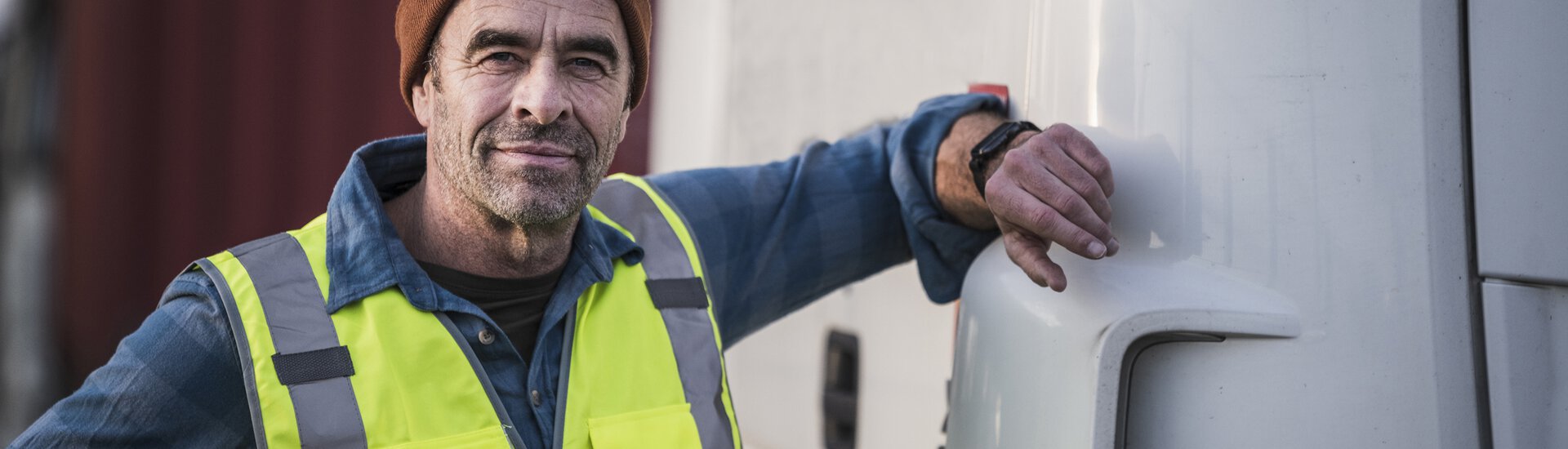älterer Mann steht an Lkw mit Hand am Fahrzeug