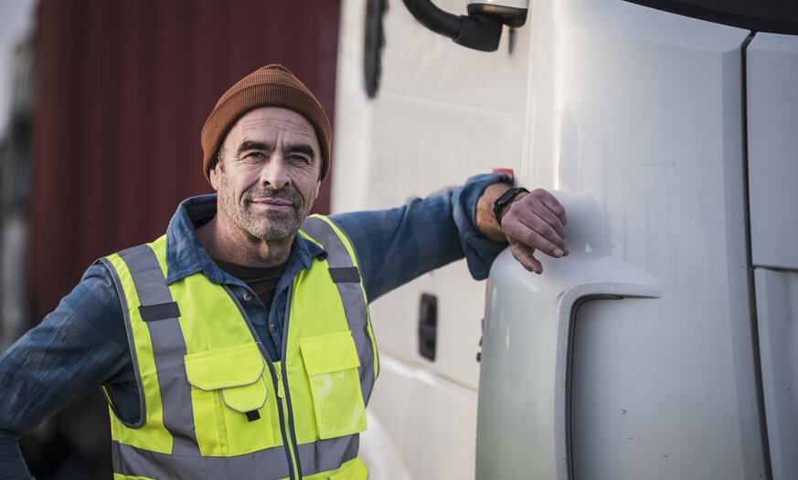 älterer Mann steht an Lkw mit Hand am Fahrzeug
