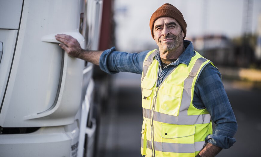 älterer Lkw-Fahrer mit Hand auf der Motorhaube