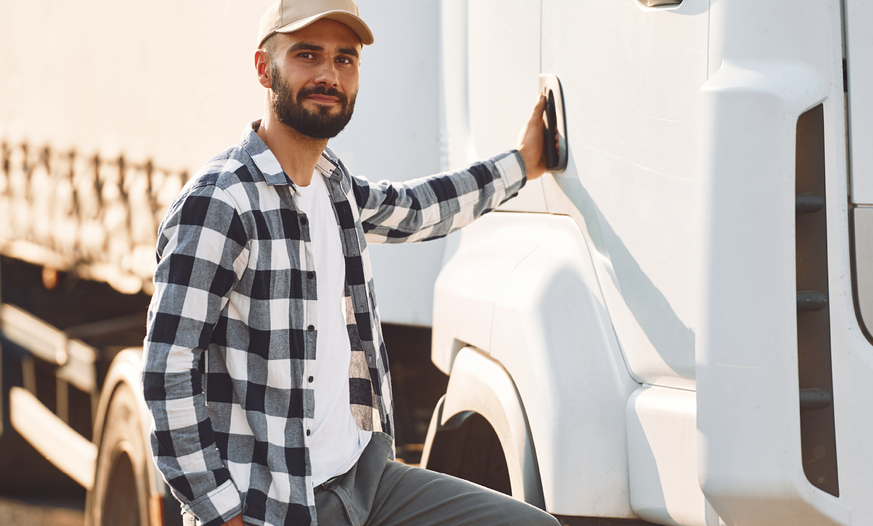 junger Mann mit Cap steigt in LKW