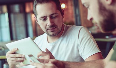 Männer sitzen in Café mit Tablet