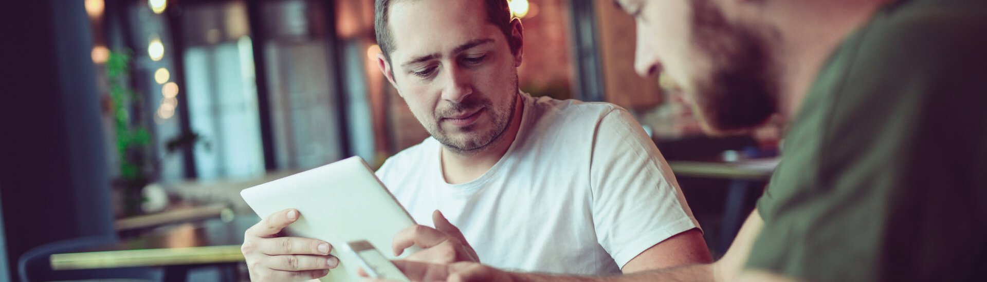 Männer sitzen in Café mit Tablet