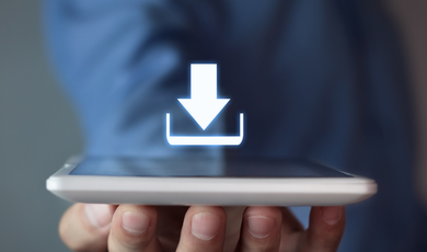 Hand, die ein mobiles Gerät mit dem Display nach oben hält und über dem Display schwebt ein Download-Symbol