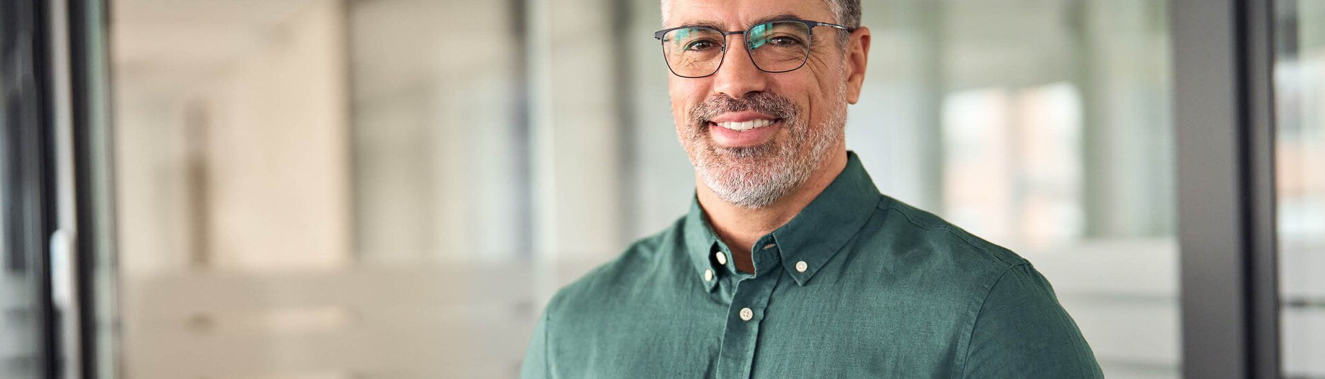 Mann mit grünem Hemd steht in Büro