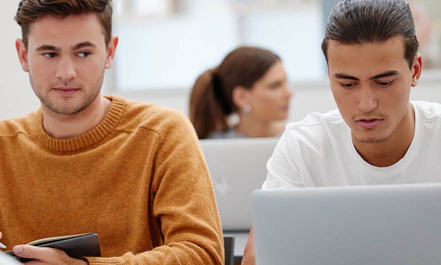 Zwei junge Männer in Prüfungssituation Junger Mann versucht abzugucken bei Nachbar in Prüfung