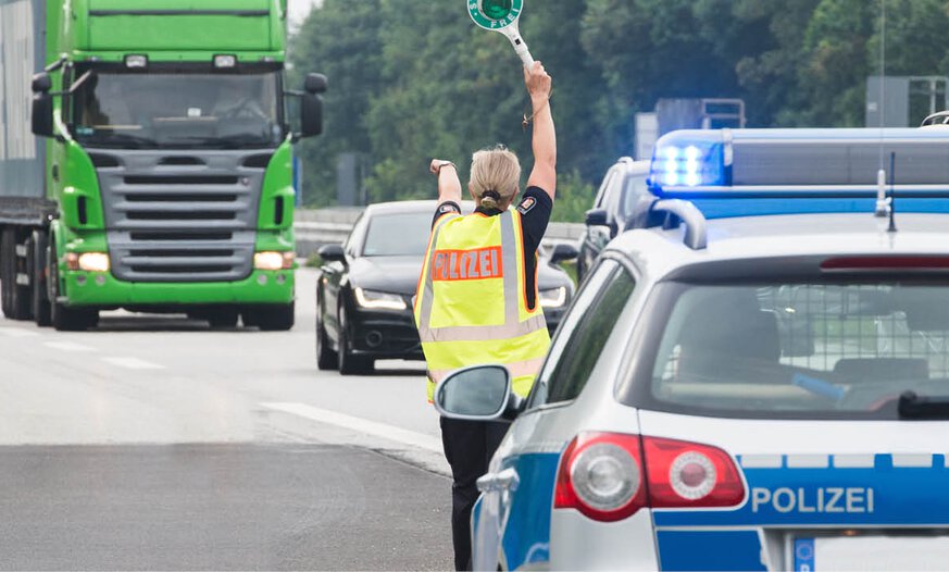Polizistin winkt LKW mit Kelle auf den Parkplatz