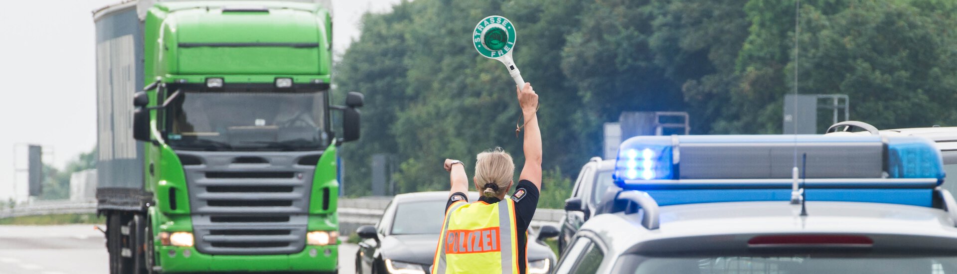 Polizistin winkt LKW mit Kelle auf den Parkplatz