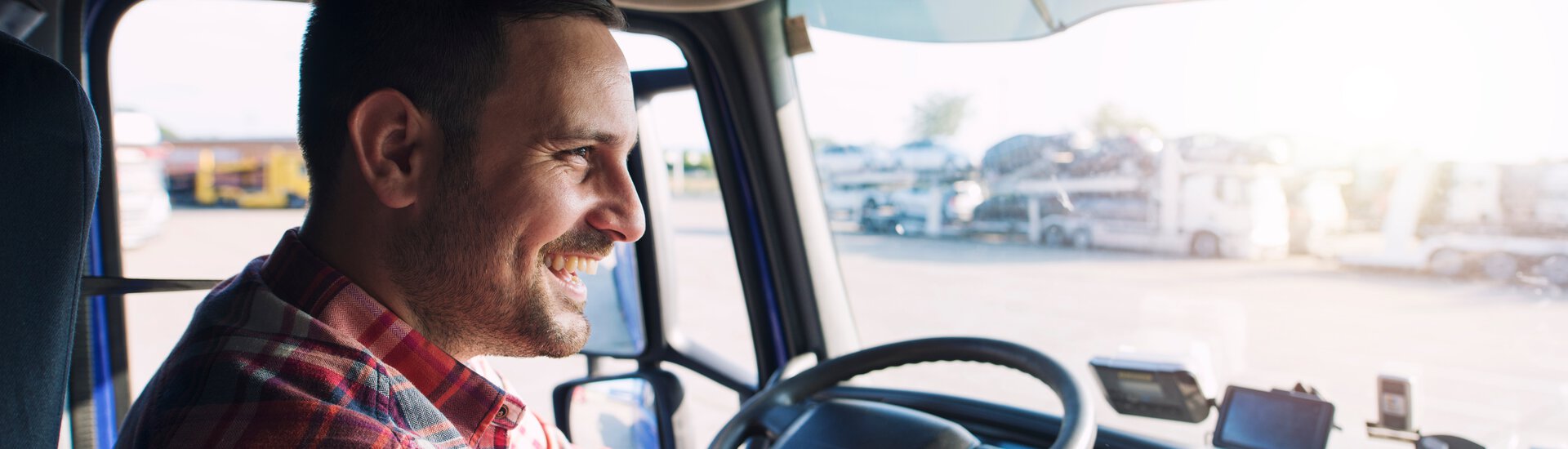 Mann mittleren Alters sitzt im Lkw und fährt freudig