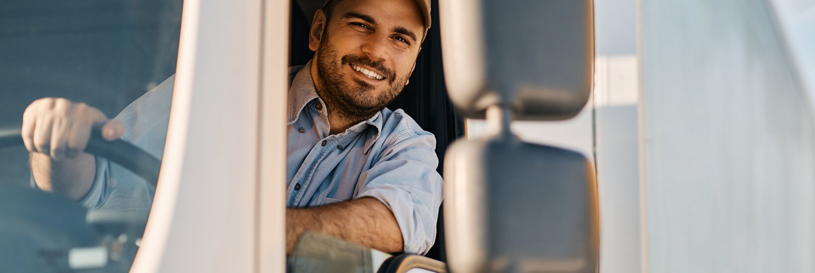 Mann in LKW Mann mit Kappe sitzt in LKW und schaut aus dem Fenster des Führerhauses