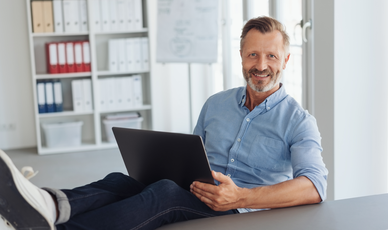 Mann mit Laptop auf dem Schoß